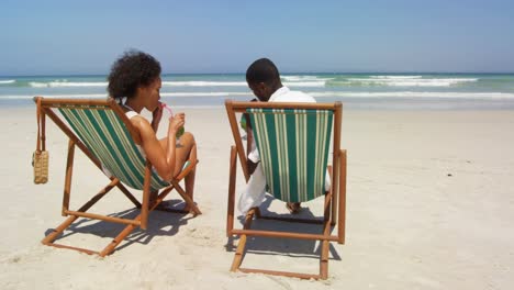 Couple-toasting-glasses-of-cocktails-at-beach-4k