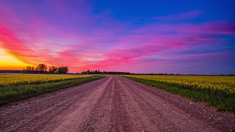 time lapse shot of beautiful multicolored sky during sunset on rural road beside canola field in peaceful wilderness - colorful sky scenery in nature