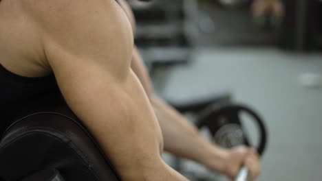 Close-up-of-man's-biceps-doing-weight-lifting-in-gym-on-bench