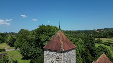 un boom-shot ascendente de la iglesia de san lorenzo el mártir en godmersham, volando por encima de la torre de la iglesia para una mayor vista de los campos detrás