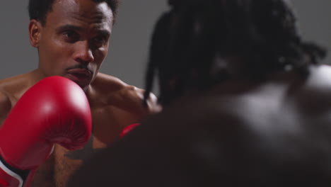 toma de estudio de cerca de dos boxeadores masculinos con guantes luchando en un partido de boxeo contra un fondo gris 10