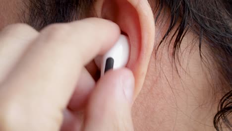 man putting on his wireless headset and adjusting it, he then presses a few buttons