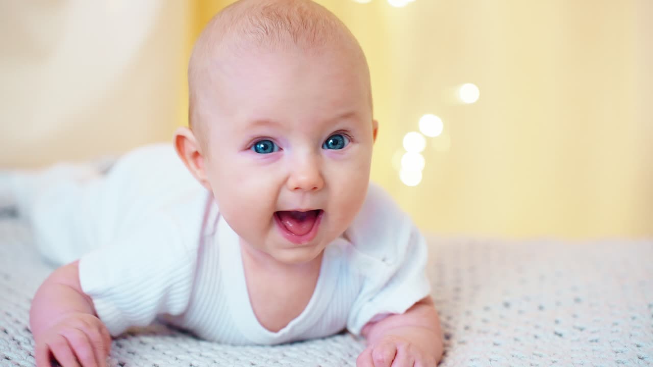 Niedliches Baby mit blauen Augen in Bauchlage schaut in die Kamera