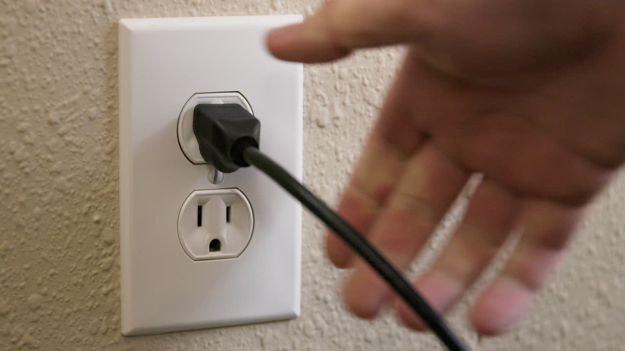 Close Up Side of Man's Hand Plugging Cord Into Electrical Outlet Then Unplugging in Slow Motion