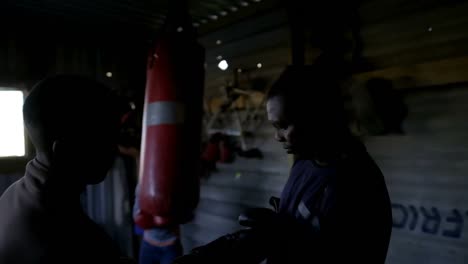 Trainer-assisting-male-boxer-in-wearing-boxing-gloves-4k