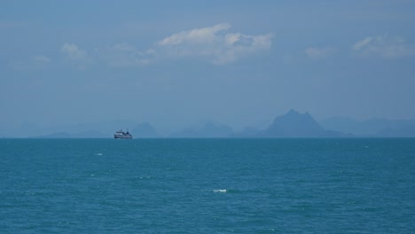 Passenger-ship-on-open-ocean-with-mountain-silhouettes-in-distance