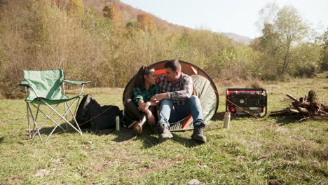 beautiful young couple having a conversation in front of their camping tent