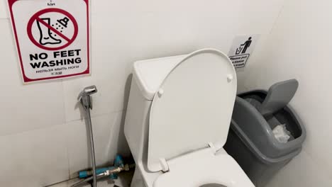 a clean public toilet with clear signage in phuket, thailand. bright lighting highlights the tiled floor and white fixtures