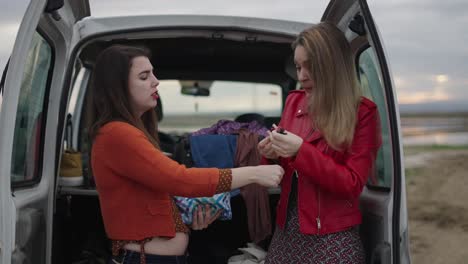 women packing for a road trip in a van
