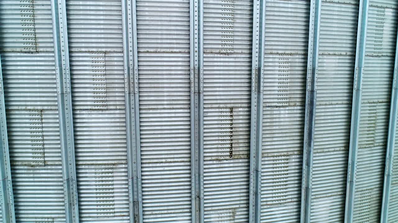 Silver metal sheathing of a modern elevator tank. Close up. Slow motion near the surface of silo cistern.