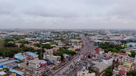 drone shot capturing cityscape with busy roads under cloudy day.