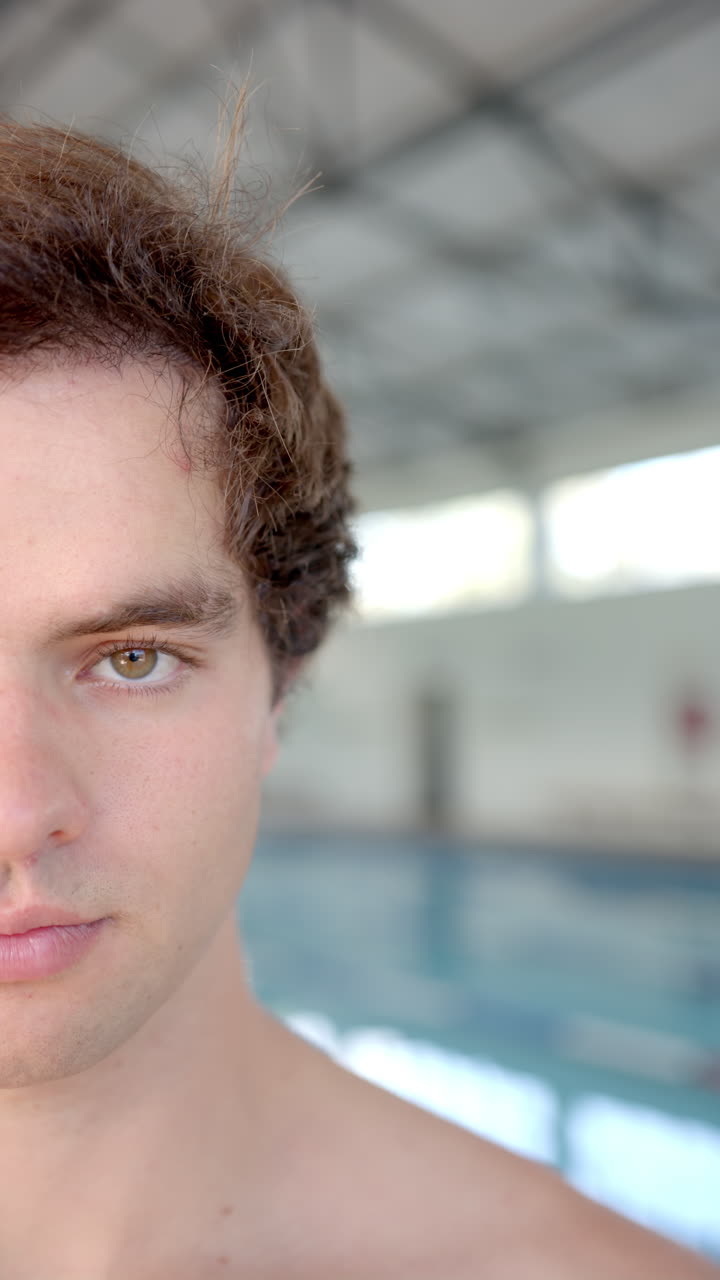 Vertical video: Swimmer posing confidently at indoor pool, preparing for swim training session