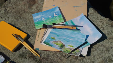 watercolor paintings and art supplies on a rock