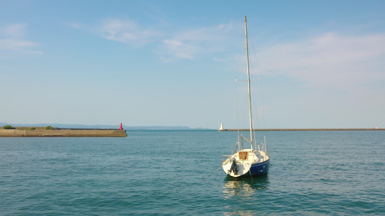 Sailboat in the sea with a lighthouse in the background