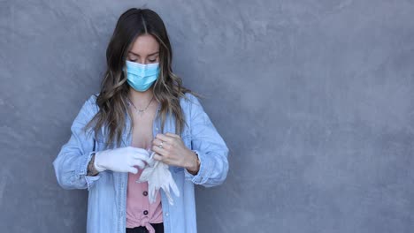 a cleared female nurse or woman with mask puts on rubber surgical gloves during the covid19 coronavirus pandemic epidemic