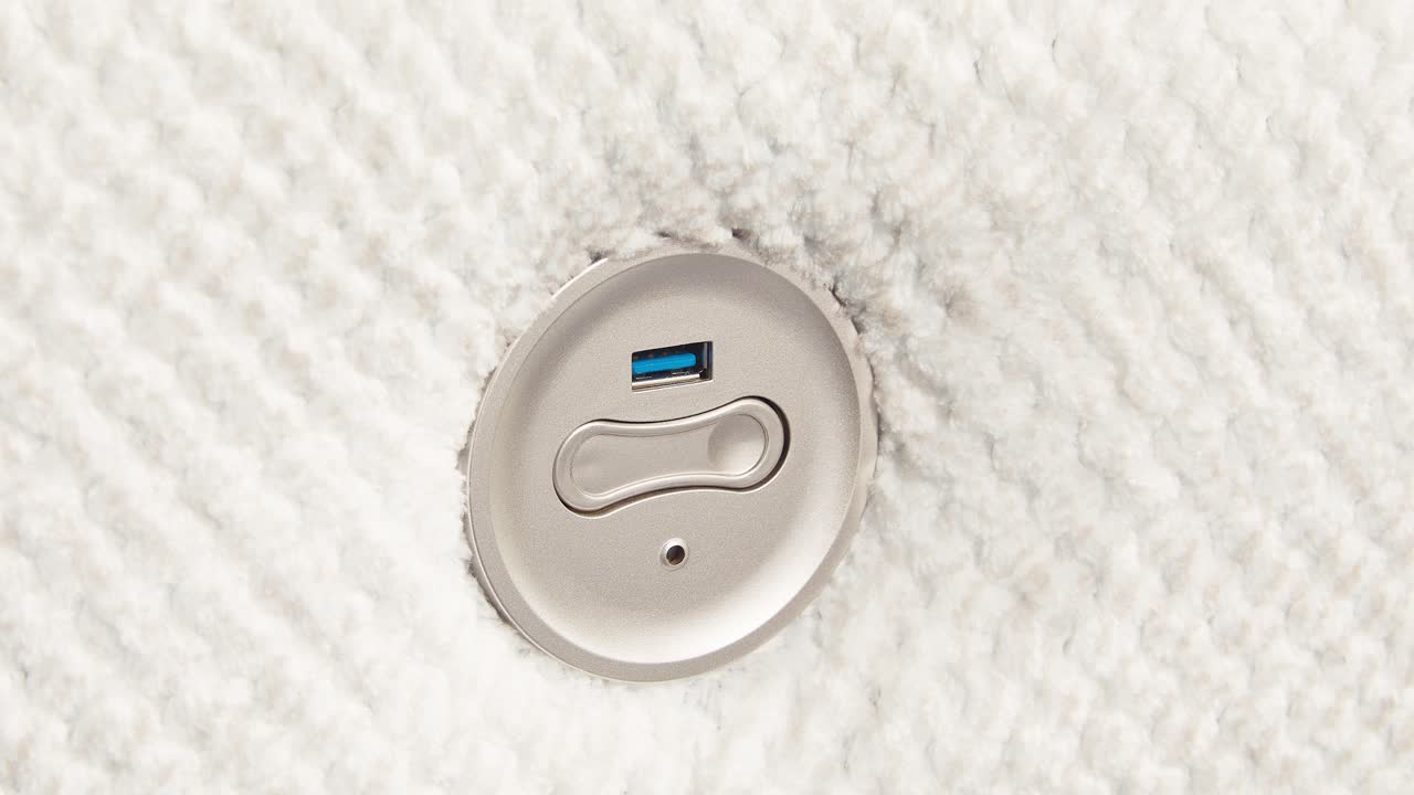 Camera slowly zooms on metal USB panel embedded in fluffy sofa side