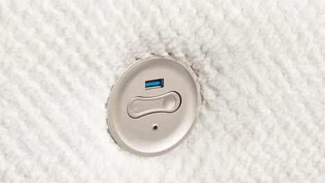 camera slowly zooms on metal usb panel embedded in fluffy sofa side