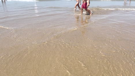 Familia-Caminando-En-Hermosas-Aguas-Claras-En-La-Playa-De-Caparica