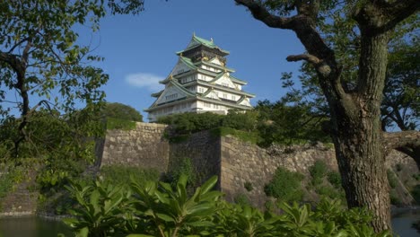 tiered tower with stone walls at osaka castle in osaka, japan. wide shot