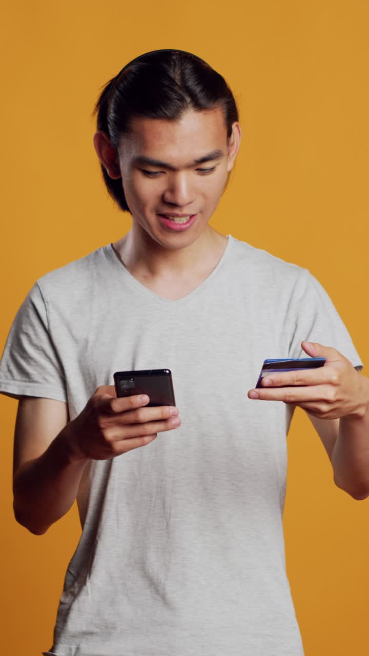 Video vertikal: Pria positif riang melakukan belanja online dengan kartu