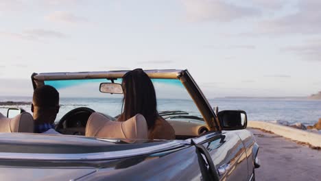 pareja afroamericana saliendo de un coche descapotable en la carretera