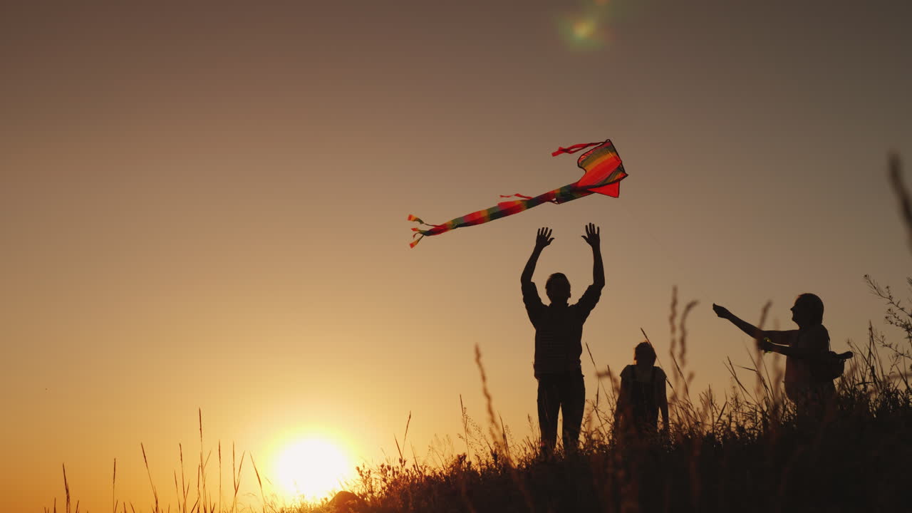 familia feliz jugando con una cometa al atardecer mamá papá e hija son felices juntos video 4k