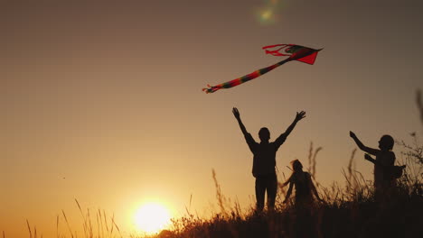 happy family playing with a kite at sunset mom dad and daughter are happy together 4k video