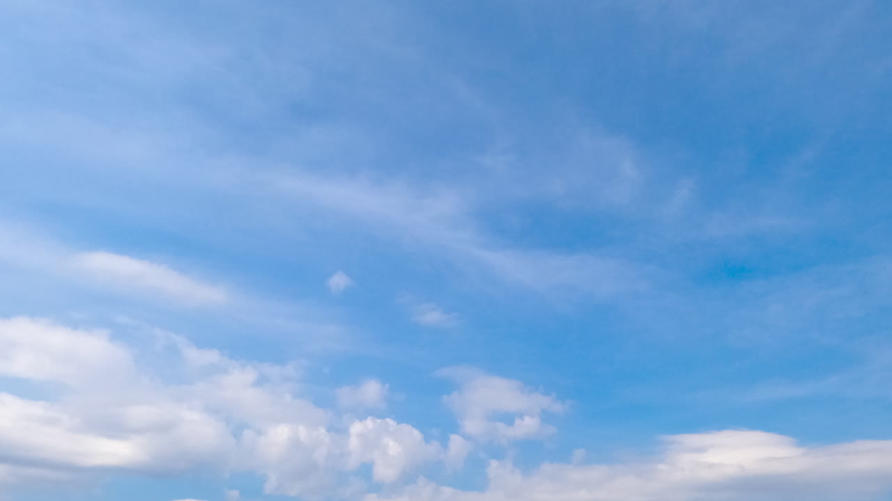 Cirro-cumulus cloudscape covering the horizon. Summer sky with light clouds at daytime. Low angle view. Timelapse.