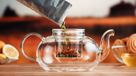 pouring loose leaf tea into a glass teapot