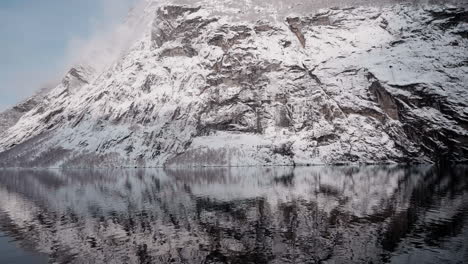 Slow-motion-POV-of-a-winter-ferry-boat-ride-in-Geirangerfjord-to-Geiranger,-Norway,-with-snowy-mountains-and-captivating-fjord-views