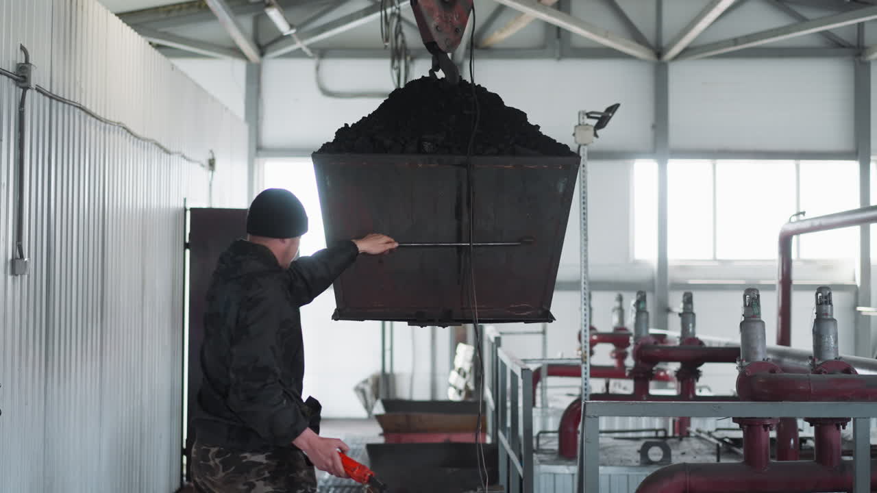 el trabajador controla el transporte del cubo de carbón en la sala de calderas