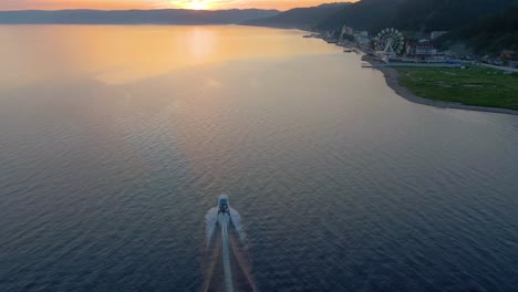 sunset over a lake with a boat and city in the background