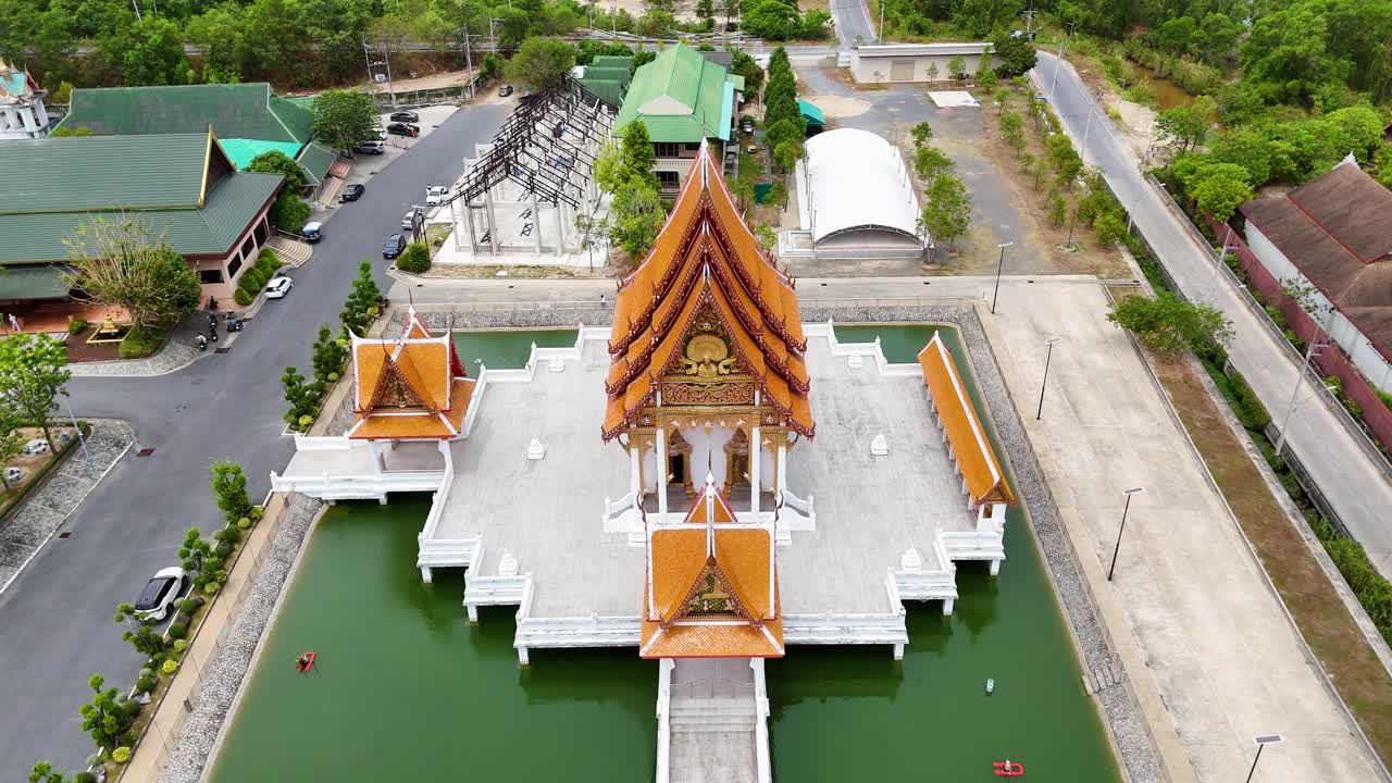 Drone footage captures a serene Buddhist temple in Phuket, showcasing its architecture and surrounding greenery under bright daylight