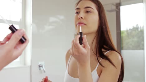 mujer hermosa aplicando brillo para los labios