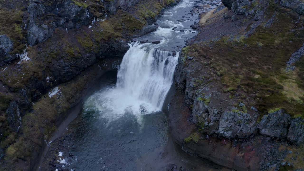 toma ascendente de arriba hacia abajo de una gran cascada que cae en el río sela durante un día nublado en la isla de islandia, europa - espectacular paisaje volcánico con agua de deshielo flotante natural