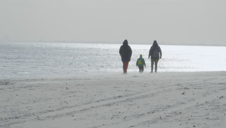 rear view of people walking by the baltic sea in gdynia backlit with setting sun light - slow motion