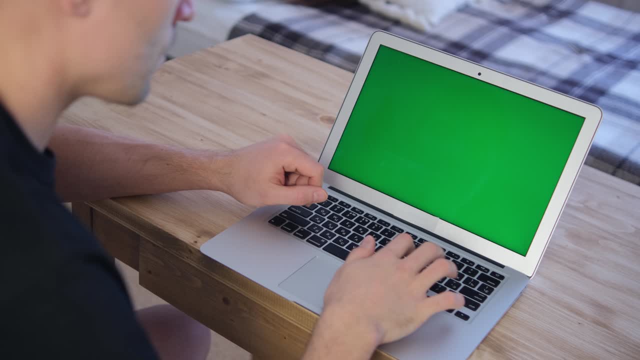 The man works remotely. Green laptop screen. Selective soft focus. The concept of distance education. Surfing the Internet