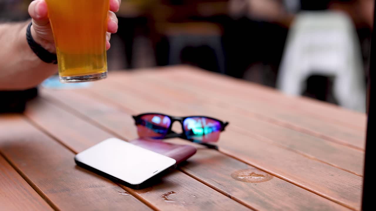 persona agarrando un vaso de cerveza de una mesa de madera