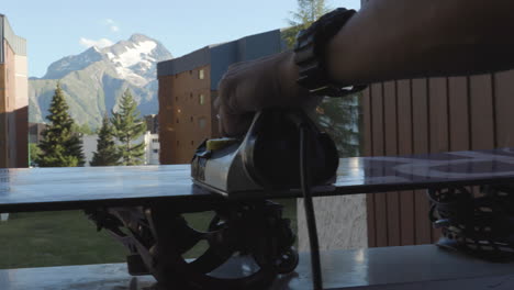 toma de detalle siguiendo la plancha mientras se aplica cera caliente en la base de la tabla de snowboard en les deux alpes