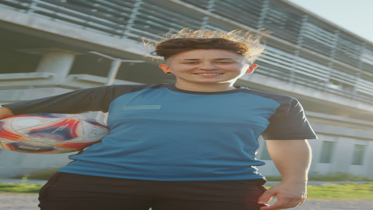 retrato de una chica sonriente sosteniendo una pelota de fútbol al aire libre en un día soleado