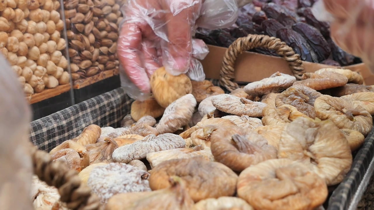 Person Selecting Dried Figs from a Market Basket