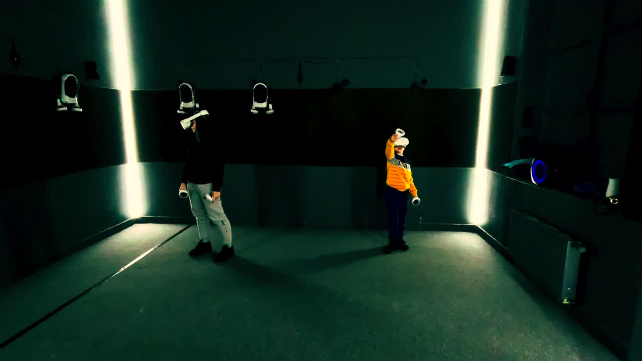 Dos niños juegan a juegos de realidad virtual dentro de una sala especialmente diseñada. El entorno cuenta con sensores de movimiento y luces brillantes que mejoran la experiencia.