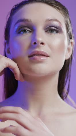 vertical video of caucasian woman with brown hair and make up touching face, copy space, slow motion