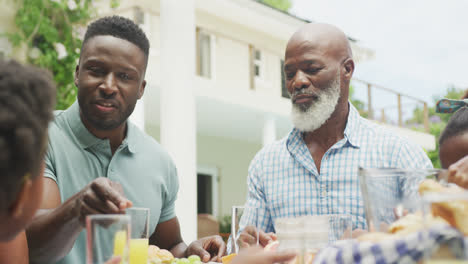 happy african american family talking and having breakfast in garden