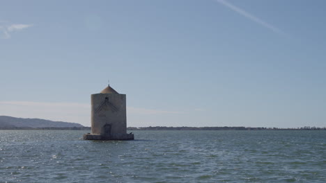 old lighthouse stands in solitude in ocean on sunny day, tuscany, maremma, italy