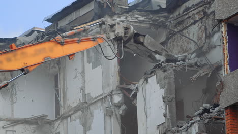 breaking concrete walls and floors with the help of machinery. dusty area of destruction site. powerful claw ruins the house. view from below.