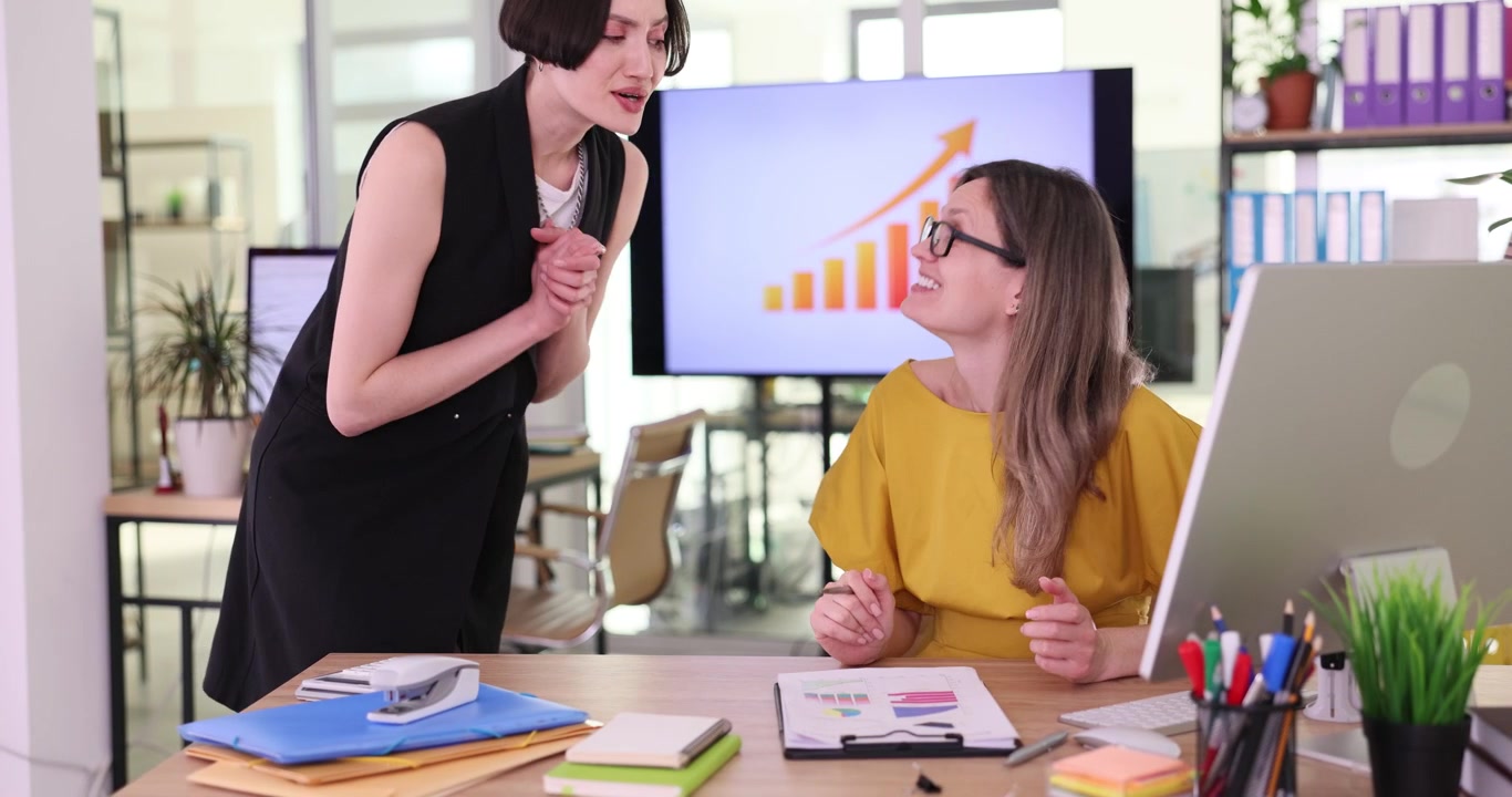 Female office workers discuss document with graphs and diagrams