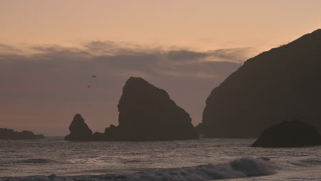 Atardecer-En-La-Costa-De-Oregon-Con-Siluetas-De-Rocas-Y-Pájaros-Volando