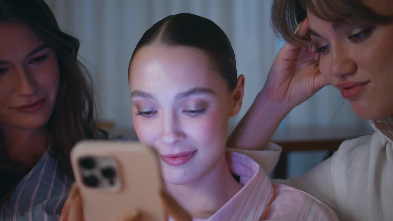 Gossiping girls watching smartphone sitting evening home closeup. Female friends