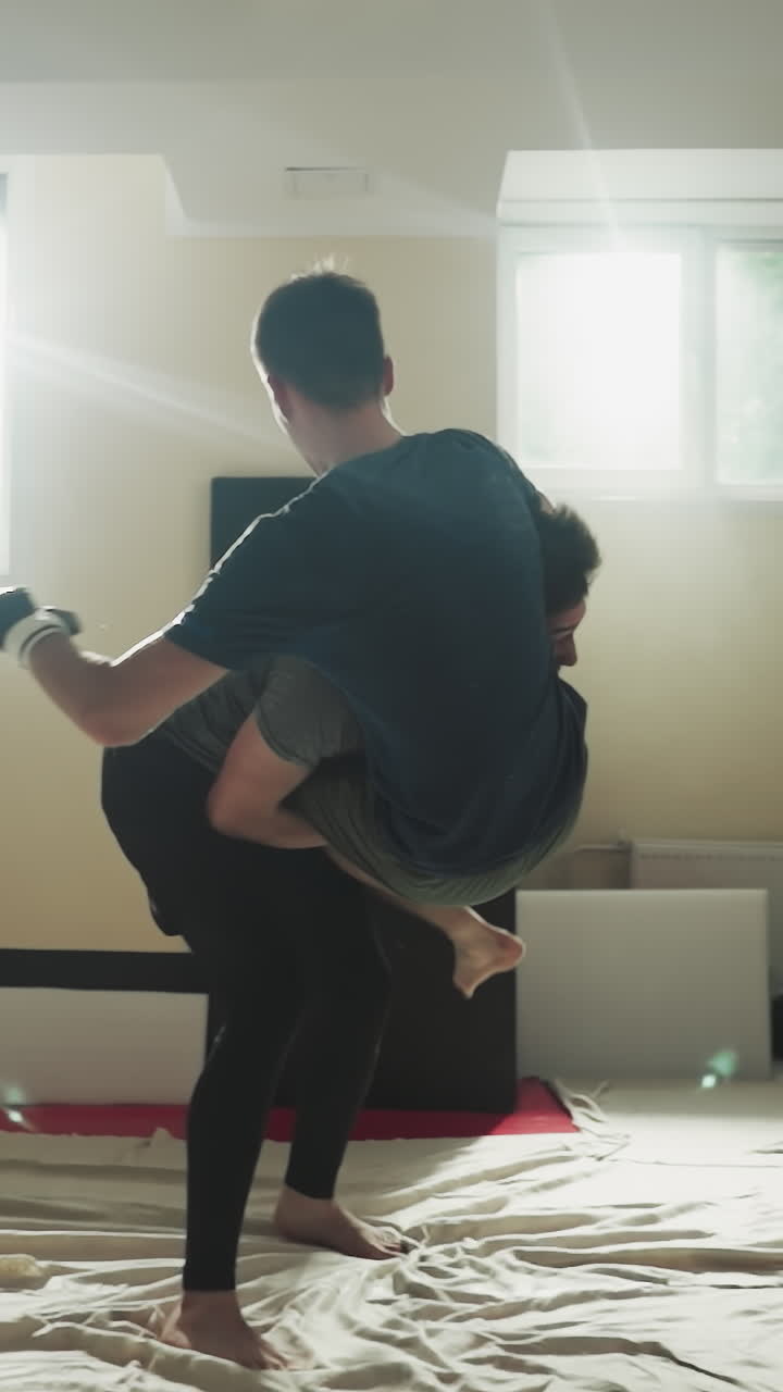 파트너를 던지고 스포츠 클럽 바닥에 주먹을 니다. 강한 운동선수들은 빛 체육관에서 스파링하는 동안 싸니다. 무술 기법